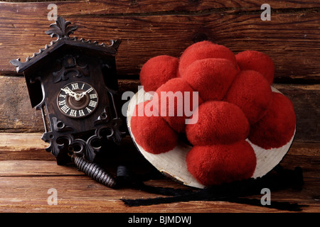 Bollenhut, Hut mit roten Pompons, Schwarzwald Tracht von unverheirateten Mädchen mit einer Kuckucksuhr auf einem rustikalen hölzernen ba Stockfoto