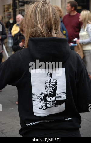 Drucken eines Mannes auf der Rückseite einer jungen Frau, die zur Förderung einer Shows während des Edinburgh Fringe Festival, Schottland an einen Stuhl gefesselt. Stockfoto