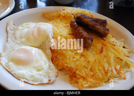 Typisches amerikanisches Frühstück von zwei Eiern, Rösti und Bratwurst Stockfoto