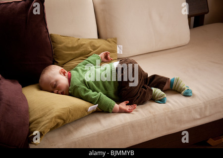 Baby Boy (elf Monate alt) schläft auf dem Sofa Hampshire England. Stockfoto