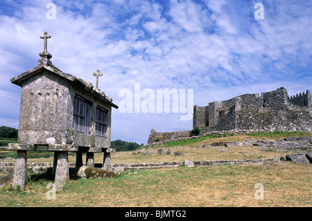 Traditionelle Spalieren oder Getreidespeicher in Lindoso, Nordportugal. Die Stadt 13. Jahrhundert Schloss ist im Hintergrund. Stockfoto