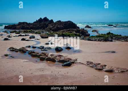 Felsen und Steinen am Strand vor dem blauen Meer an der Küste der Algarve in Portugal Stockfoto