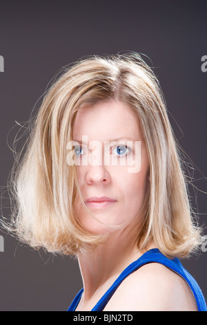 Bildnis einer blonden Frau mit blauen Augen - isoliert auf dunklem Hintergrund Stockfoto
