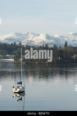 Yachten im Waterhead am Lake Windermere im englischen Lake District mit Schnee auf den Langdale Pikes im Hintergrund. Stockfoto