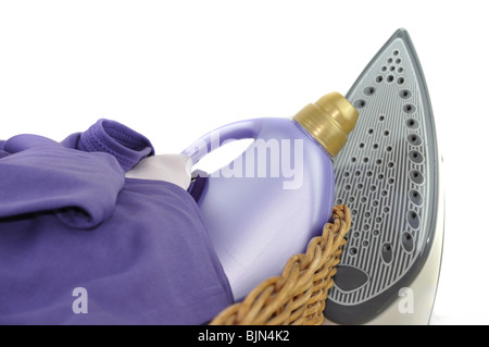 Ein Waschmittel Flasche und lila Wäsche in einem Weidenkorb mit Eisen, isoliert auf weiss Stockfoto
