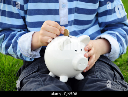 Horizontales Bild eines jungen, Geld in sein Sparschwein Stockfoto