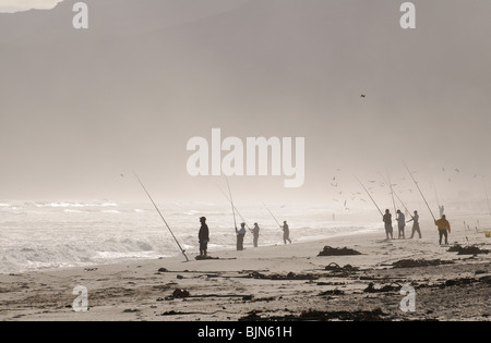 Männer Angeln vom Strand an der False Bay bei Muizenberg in der western Cape Südafrika gesehen aber die helle Abendsonne und se Stockfoto