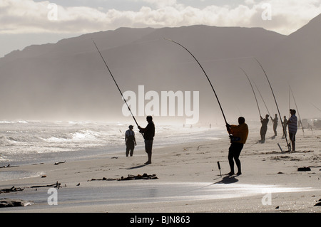 Männer Angeln vom Strand an der False Bay bei Muizenberg in der western Cape Südafrika gesehen aber die helle Sonne Stockfoto