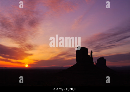 Sunrise schafft eine Silhouette der Fäustlinge in Monument Valley National Park, Arizona Stockfoto