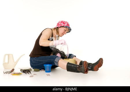 Eine Frau Gummi Stiefel gießt Boden in einem Blumentopf. Stockfoto