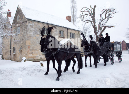 Traditionelle alte altmodische Pferdekutsche Beerdigung Schlitten im Schnee mit vier Pferden bereit für Gottesdienst verlassen Stockfoto