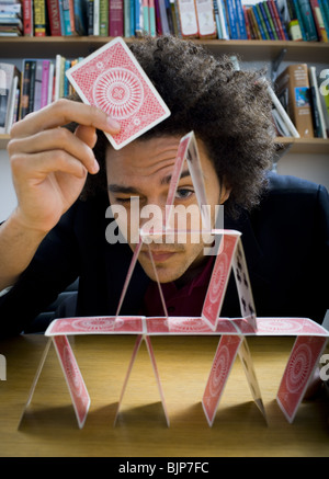 Mann, der eine Pyramide aus Spielkarten Stockfoto