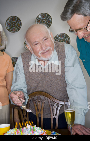 Partygänger rund um einen Geburtstagskuchen Stockfoto