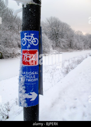 Radweg-Wegweiser durch Kanal im winter Stockfoto