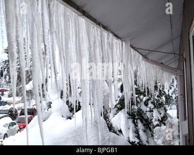 Eiszapfen hängen von Dachtraufe Stockfoto