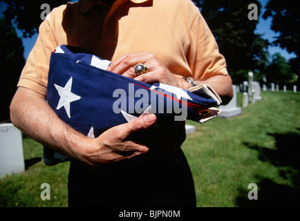 Mann mit gefalteten Flagge bei militärischen Beerdigung Stockfoto