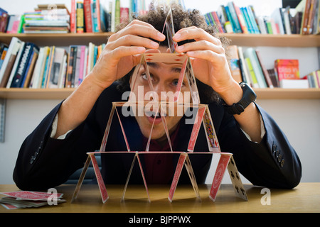 Mann, der eine Pyramide aus Spielkarten Stockfoto