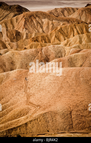 Wanderer in den Badlands am Zabriskie Point mit Blick auf Golden Canyon in Death Valley Nationalpark, Kalifornien, USA. Stockfoto