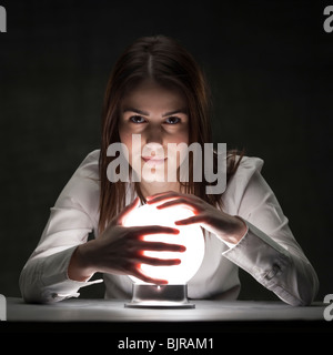 Studio-Porträt der jungen Frau, die mit Crystal ball Stockfoto