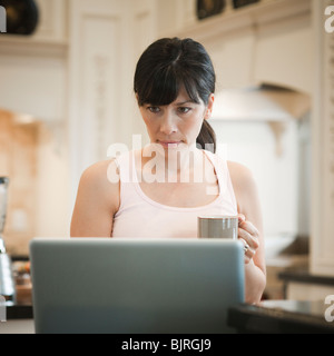 USA, Utah, Alpine, Mitte Erwachsene Frau stehen in der Nähe von Laptop und hält Becher Stockfoto