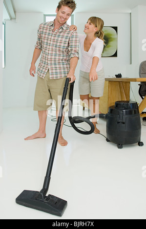 Frau zeigt als Mann Staubsauger Stockfoto