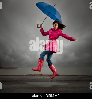 USA, Utah, Orem, Frau mit Regenschirm springen unter bewölktem Himmel Stockfoto