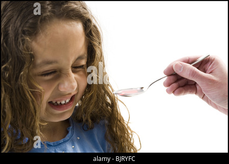 Junge Mädchen, die einen Löffel der Medizin Stockfoto