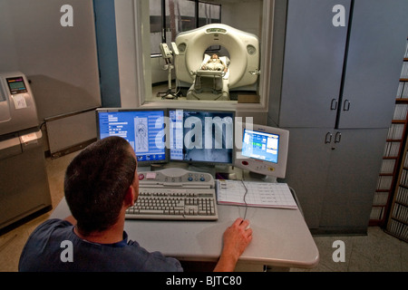 An eine Steuerung der Konsole sitzen, bereitet ein Medizintechniker für eine CT-Untersuchung in einer California Radiologie Klinik. Stockfoto