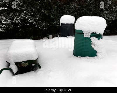 Zwei Komposter und eine Schubkarre im Schnee im Garten Surrey England Stockfoto