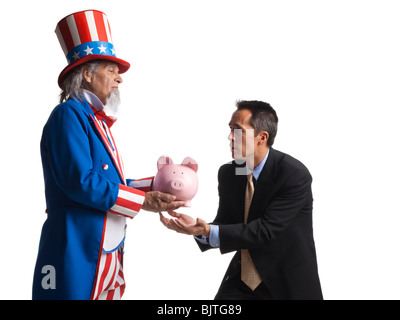 Mann in Uncle Sam Kostüm geben Sparschwein zu anderen Menschen, Studio gedreht Stockfoto