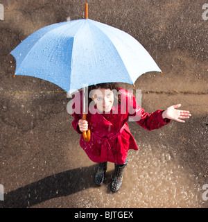 Junge Frau im Regen mit Regenschirm Stockfoto