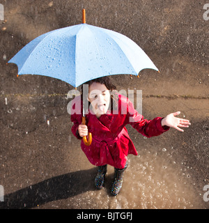 Junge Frau im Regen mit Regenschirm Stockfoto