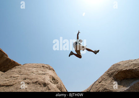 Mann zwischen großen Felsbrocken springen Stockfoto