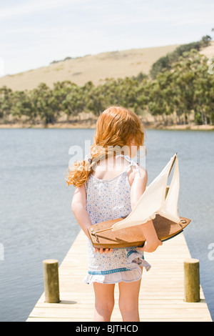 Mädchen am Hafenkai mit Spielzeugboot Stockfoto