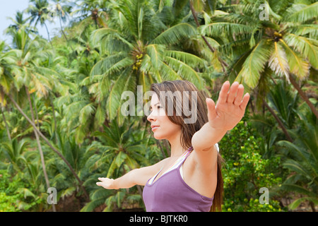 Frau, Yoga zu praktizieren, von Palmen Stockfoto