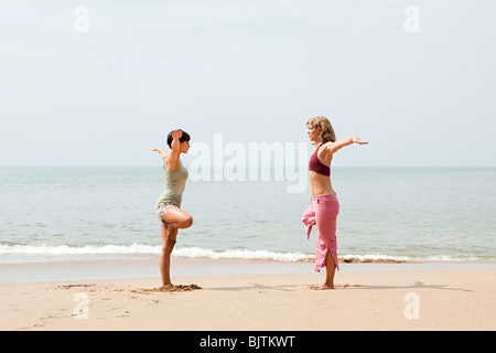 Zwei Frauen praktizieren Yoga am Strand Stockfoto