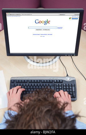 Overhead Schuss eines Mannes saß an einem Schreibtisch arbeiten am Computer, Google-Seite im Internet. Stockfoto