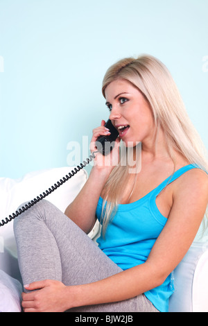 Junge, blonde Frau saß in einem Sessel am Telefon sprechen
