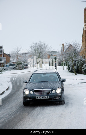 Mercedes Auto auf Schnee bedeckt eine Wohnsiedlung in England unterwegs. Stockfoto
