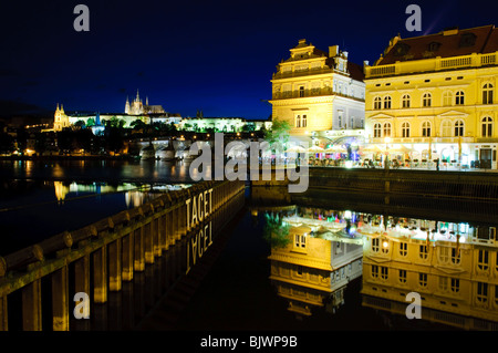 Karlsbrücke und Bedrich-Smetana-Museum auf der Moldau bei Nacht Prag // PRAG, Tschechische Republik — das Bedrich-Smetana-Museum, das in einem ehemaligen Wasserwerk der Neorenaissance untergebracht ist, wird am Ufer der Moldau beleuchtet, wobei die Kunstinstallation „Tacet“ von Jiří David auf dem Wehr im Vordergrund zu sehen ist. Das Museum ist dem Leben und Werk des berühmten tschechischen Komponisten Bedřich Smetana aus dem 19. Jahrhundert gewidmet. Im Hintergrund überspannt die mittelalterliche Karlsbrücke (Karlův Most) den Fluss, auf dem Hügel ist die riesige Prager Burg (Pražský hrad) zu sehen. Aufbau der GOT Stockfoto