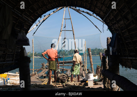 Indien, Kerala, Kochi, Fort Cochin, Männer, die auf chinesischen Fishing Net Stockfoto