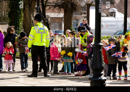 Kleinkindern Line-up außerhalb Derby Kathedrale die Königin nach der Zeremonie Maundy Money, freundliche Polizei erfüllen helfen. Stockfoto