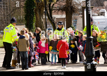 Kleinkindern Line-up außerhalb Derby Kathedrale die Königin nach der Zeremonie Maundy Money, freundliche Polizei erfüllen helfen. Stockfoto