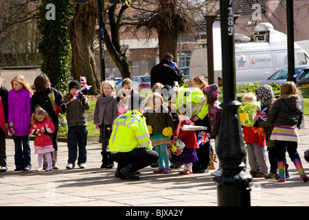 Kleinkindern Line-up außerhalb Derby Kathedrale die Königin nach der Zeremonie Maundy Money, freundliche Polizei erfüllen helfen. Stockfoto