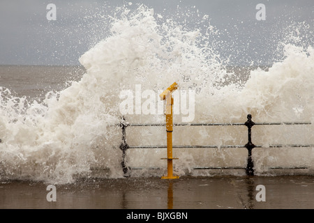 Rauhe See in Scarborough während einer Springflut. Wellen brechen über eine gelbe Teleskop an der nördlichen Strandpromenade Stockfoto