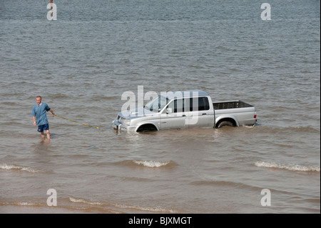 Auto / LKW / SUV stuck im weichen Sand am Strand bei Flut kommen in Stockfoto