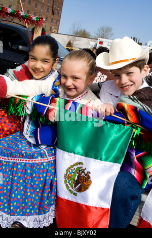 Drei hispanischen und weißen Kinder in traditionelle mexikanische Kleidung hält mexikanische Flagge. Cinco De Mayo Fiesta St Paul Minnesota USA Stockfoto