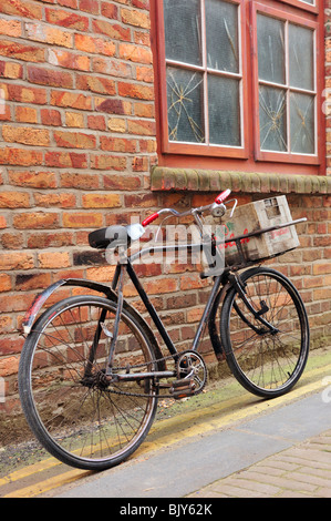 SCARBOROUGH, NORTH YORKSHIRE, Großbritannien - 19. MÄRZ 2010: Old Delivery Bike Leaning Against Brick Wall Stockfoto