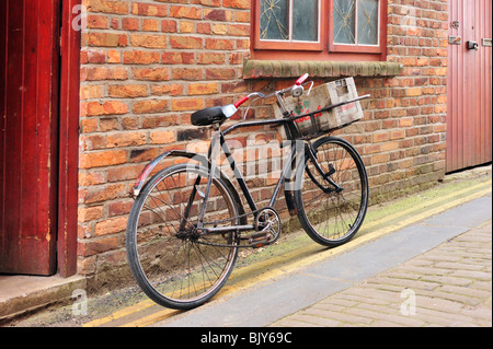 SCARBOROUGH, NORTH YORKSHIRE, Großbritannien - 19. MÄRZ 2010: Old Delivery Bike Leaning Against Brick Wall Stockfoto