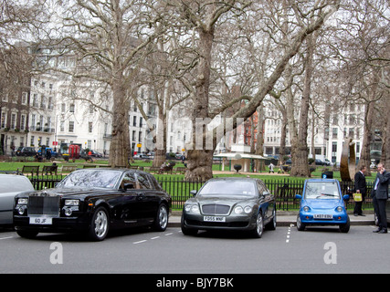Rolls-Royce, Bentley und G-Wiz Elektroauto geparkt in angrenzenden Buchten in Berkeley Square, Mayfair, London Stockfoto